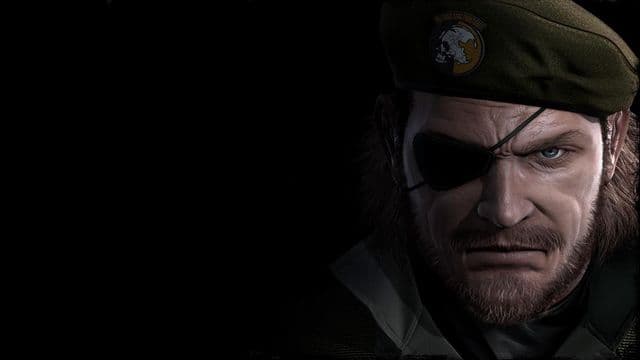 Primer plano del rostro de Big Boss saliendo de la oscuridad: parche en el ojo, barba corta y boina verde oliva con el emblema de la calavera de Militaires Sans Frontières.